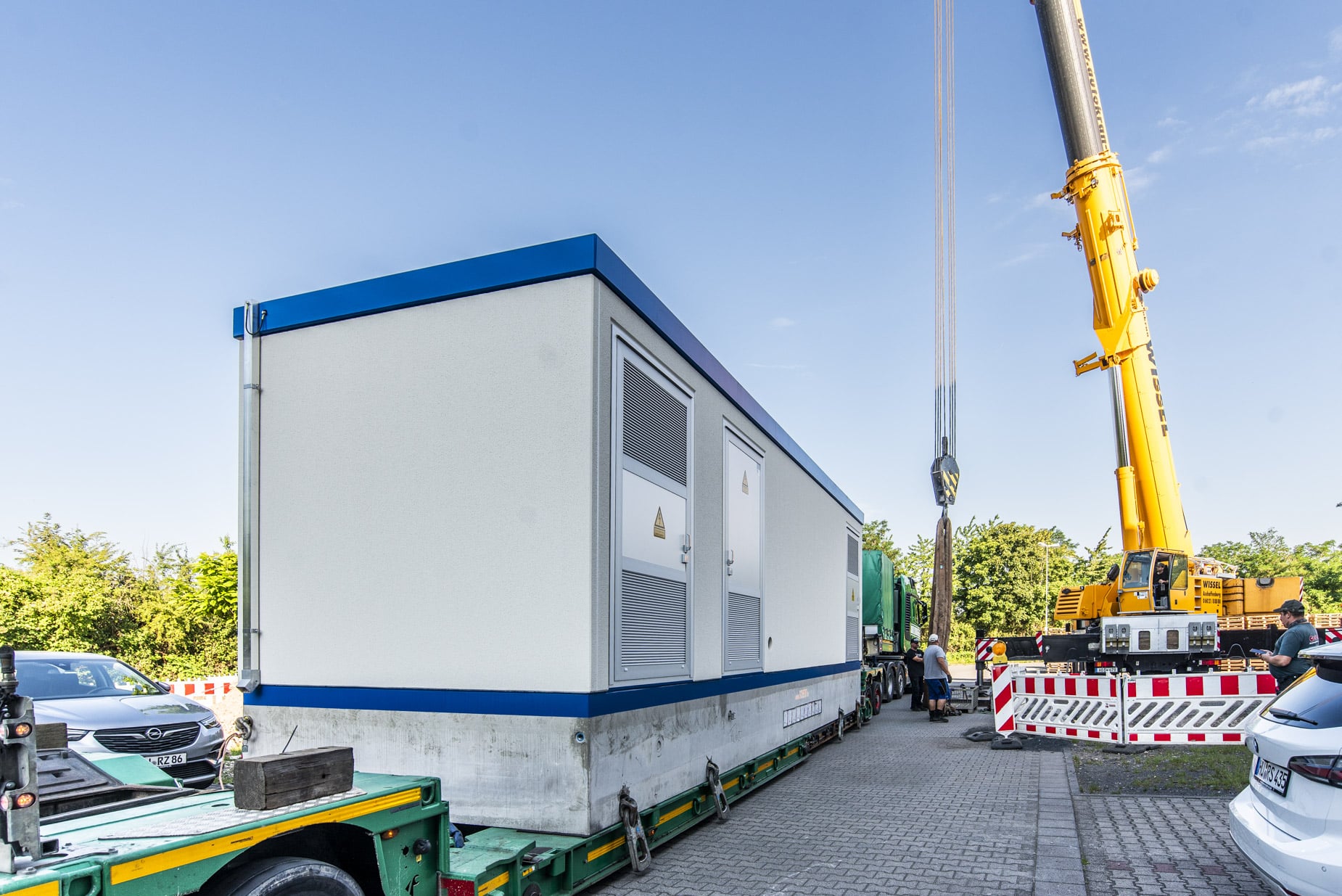 Trafos / Trafostationen Kran stellt eine Container-Trafostation am Einsatzort auf