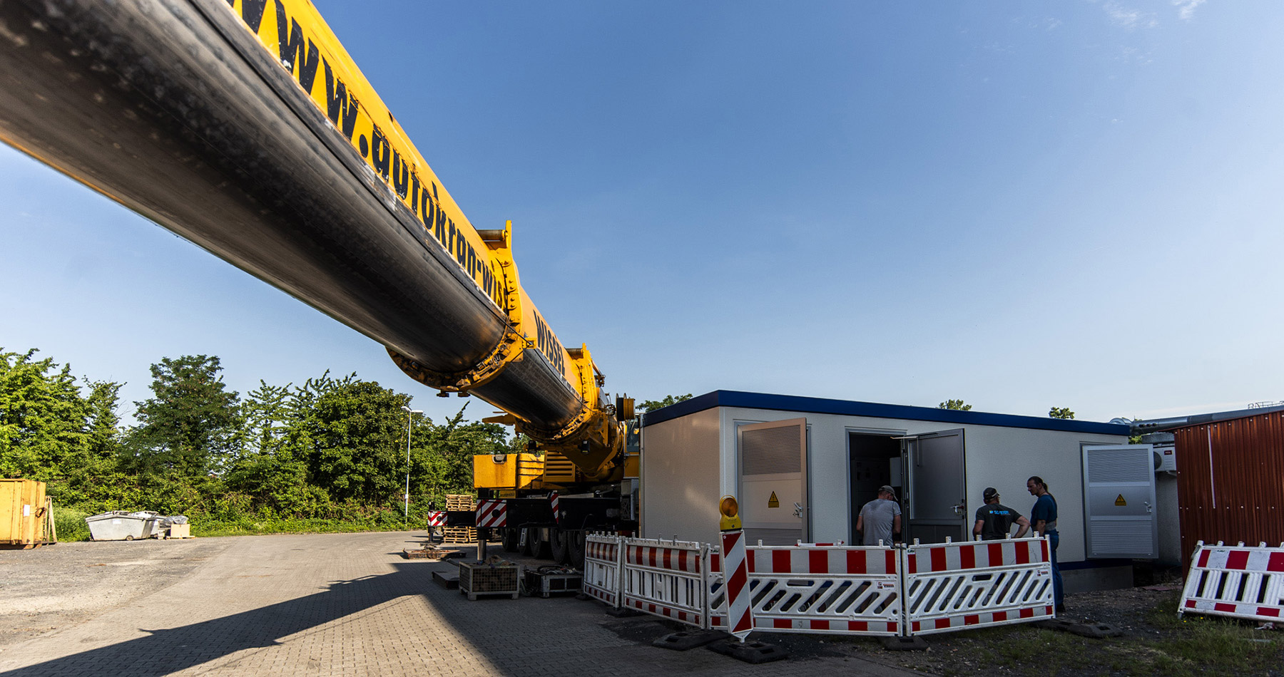 60-Tonnen-Trafostation mit Schwerlastkran erfolgreich aufgestellt Schwerlastkran und Mitarbeiter an der aufgestellten 60-Tonnen-Trafostation