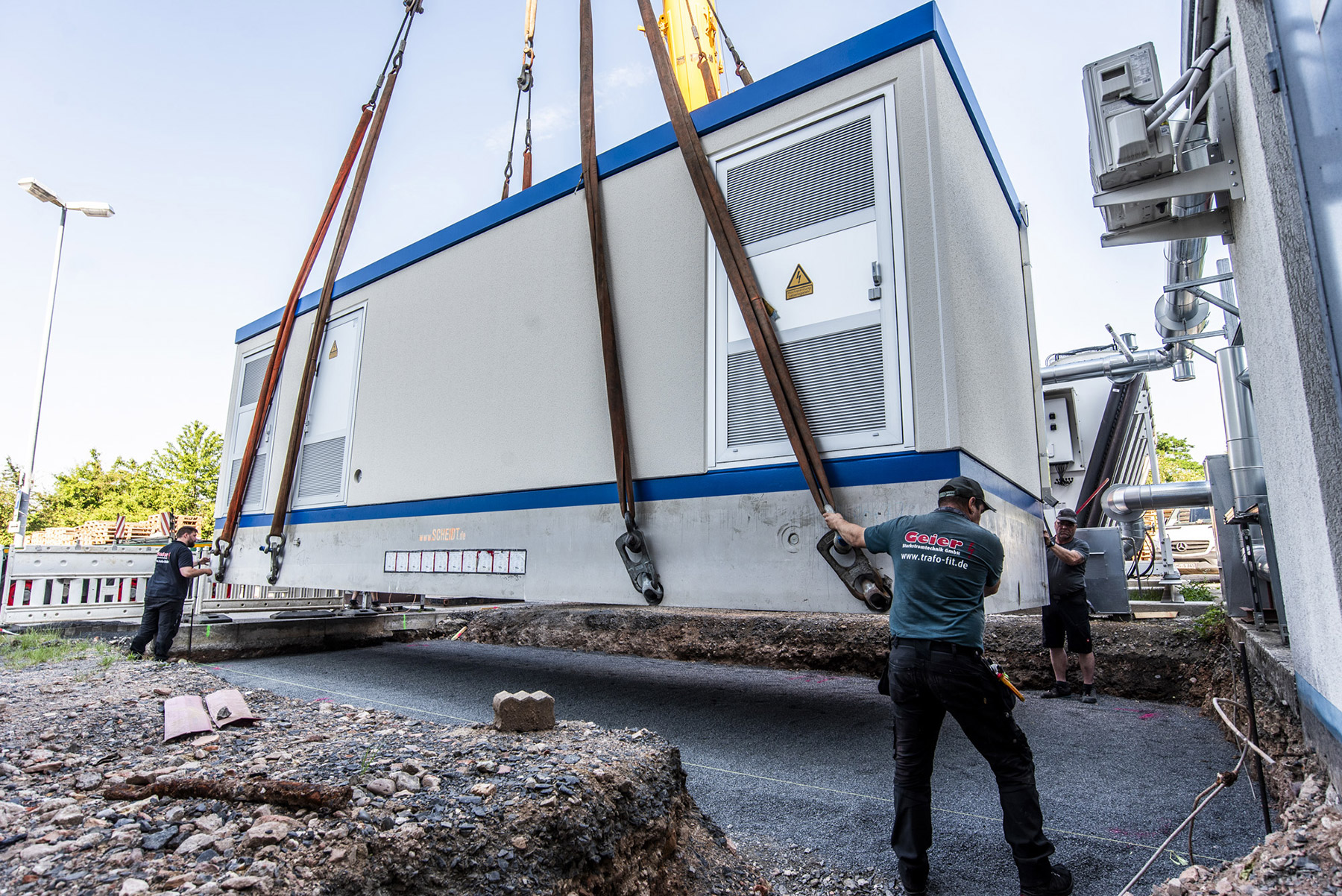 60-Tonnen-Trafostation mit Schwerlastkran erfolgreich aufgestellt Mitarbeiter positionieren eine 60-Tonnen-Trafostation während des Kranhubs