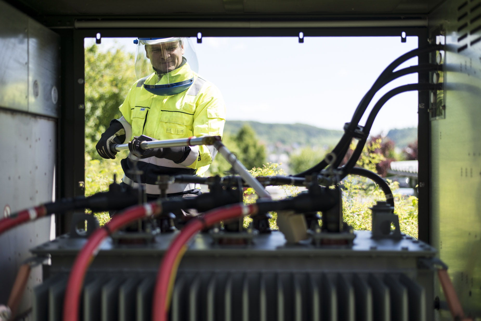Trafos / Trafostationen Elektriker beim Anschließen der Kabel an einen Transformator in einer Trafostation